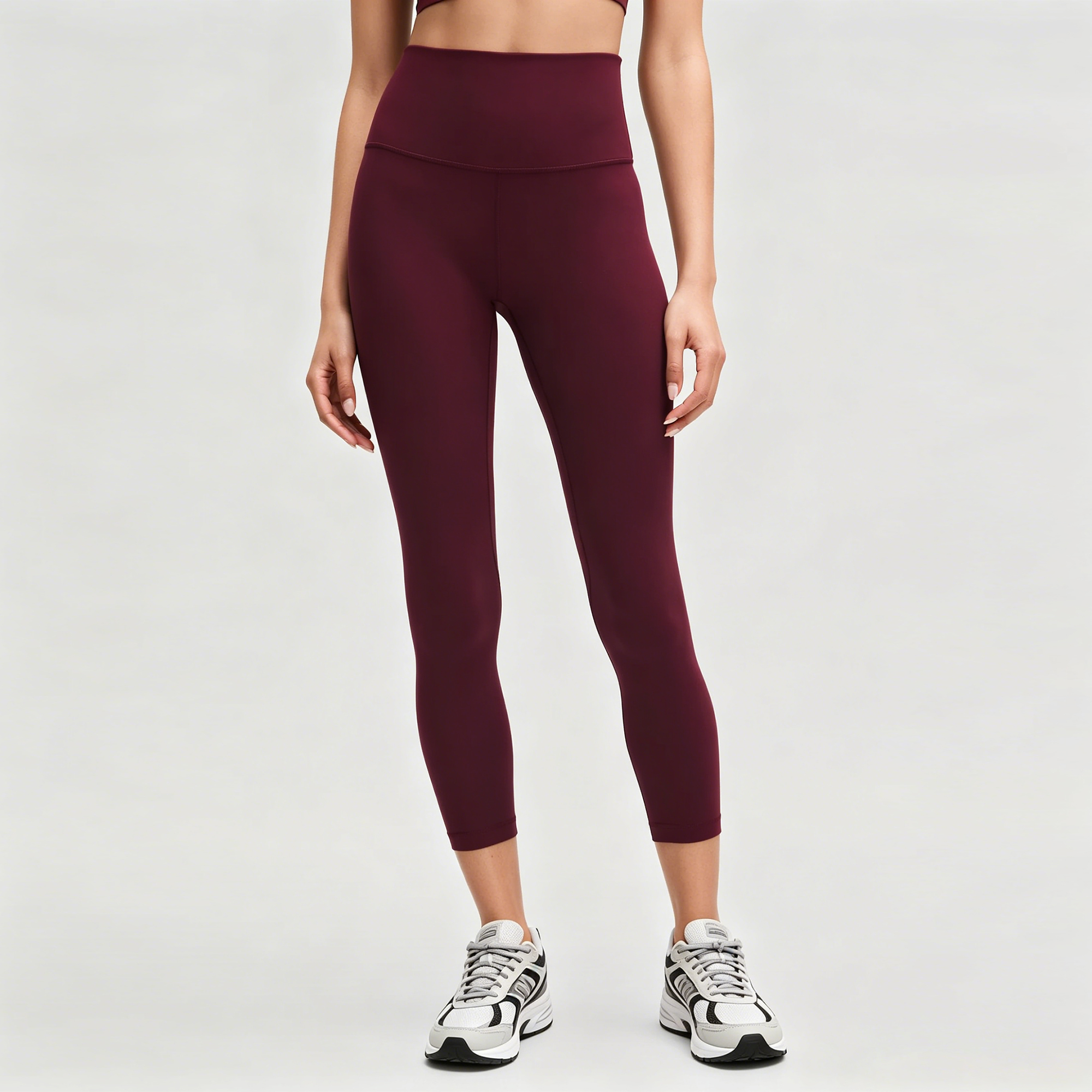 Burgundy high-waisted cropped leggings with a wide seamless waistband, worn with white trainers